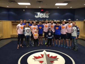 Winnipeg Jets players posing with Alyx and her family in the Jets dressing room. Photo taken from cbc.ca